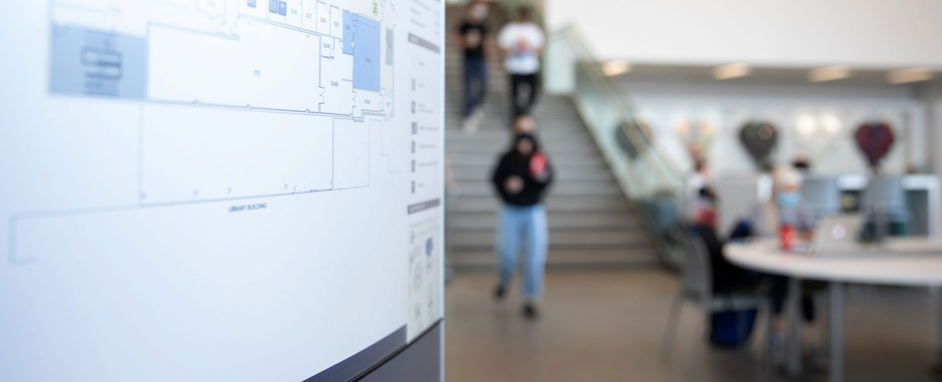 Floorplan of Fitz Hall at UBC Okanagan, with students studying in the background.